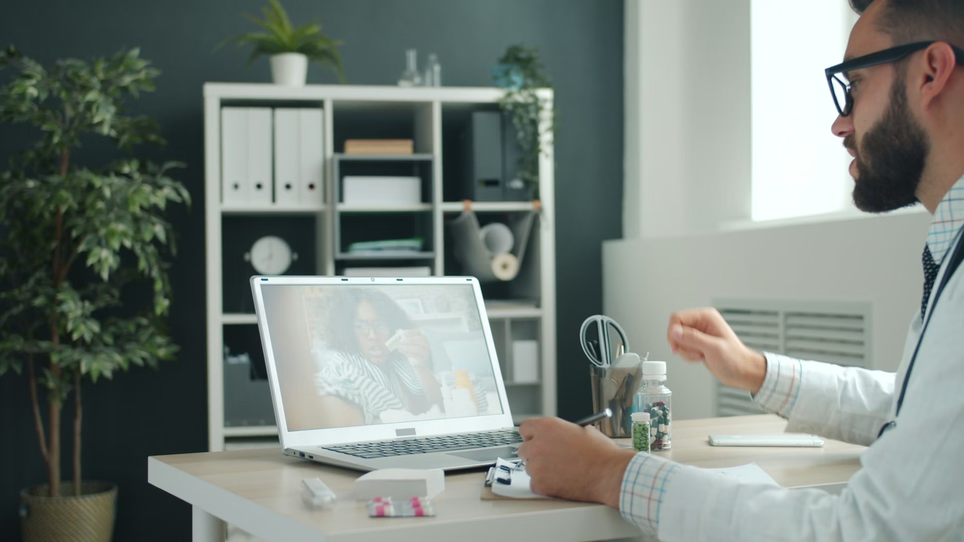 A person holding a tablet showing a video call with a doctor.